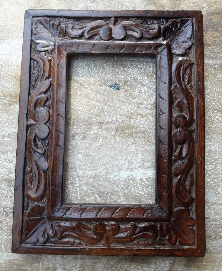 an old wooden frame with carvings on the edges and sides, hanging on a wall