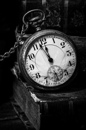 black and white photograph of an old pocket watch on top of a pile of books