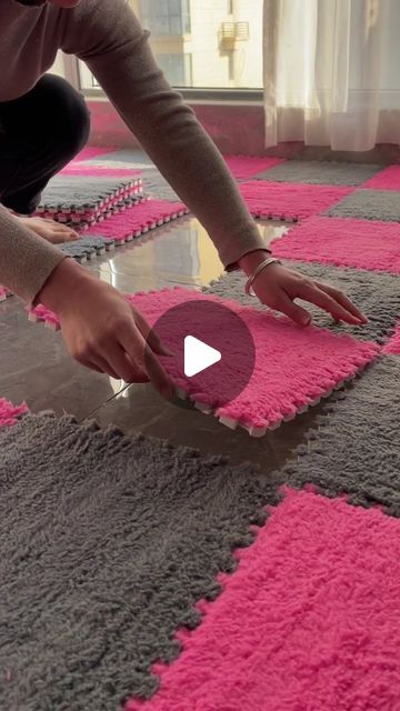 a woman kneeling down on top of a pink and gray rug