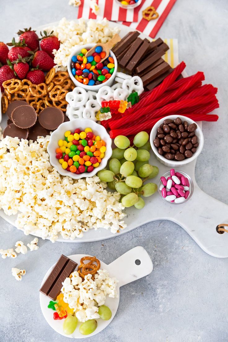 a platter filled with candy, popcorn, and other snacks on top of a table