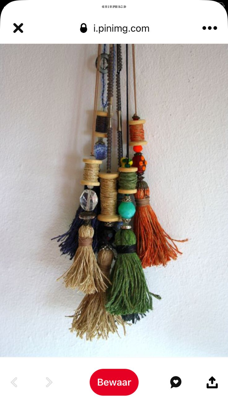 a bunch of spools of thread hanging from a hook on a white wall