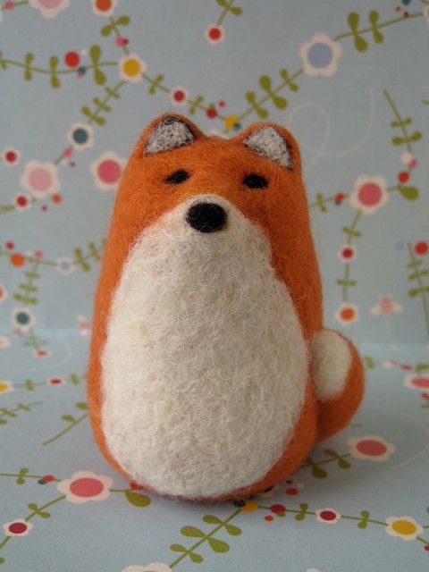 an orange and white stuffed animal sitting on top of a blue table cloth covered with flowers