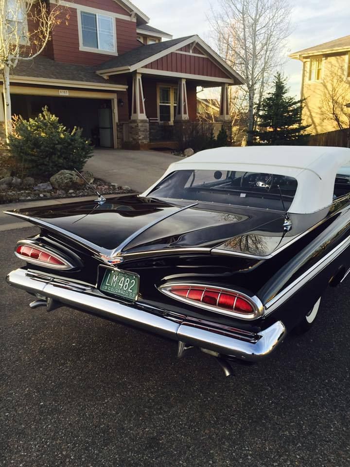 an old black and white car parked in front of a house