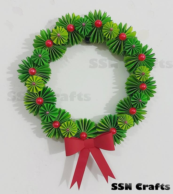 a paper wreath with red bows and green decorations