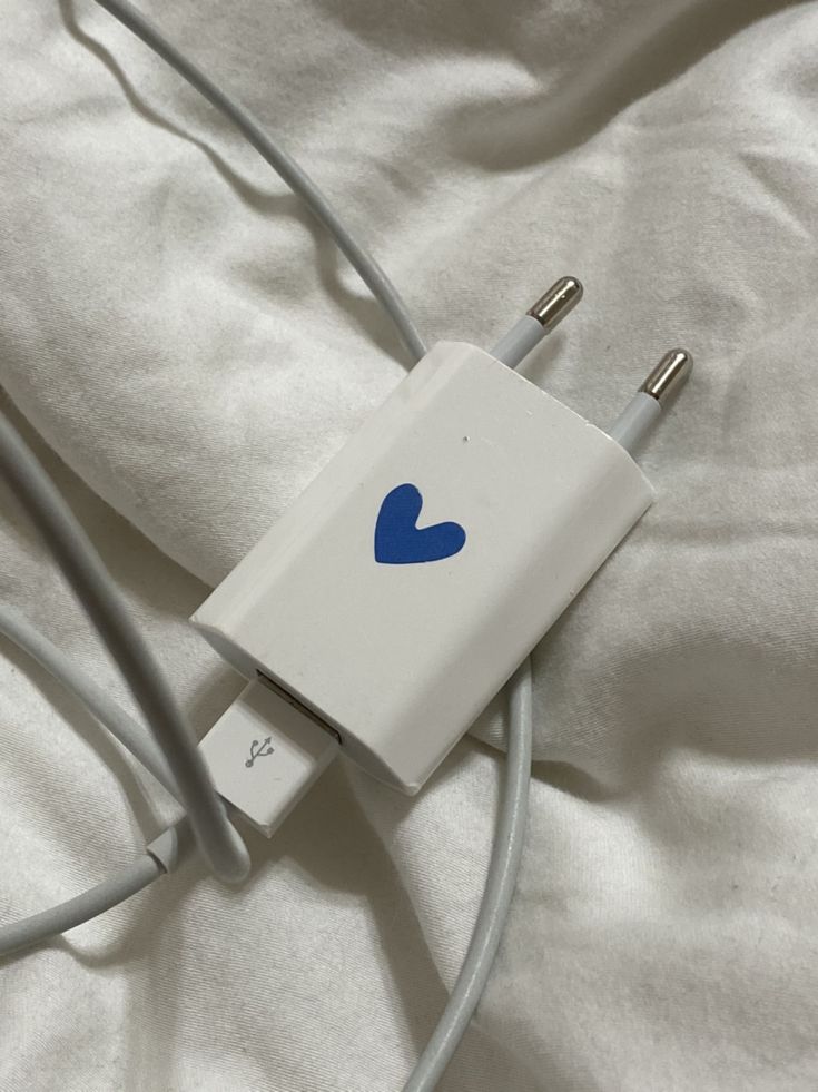 an apple charger plugged in to a white cord on top of a bed