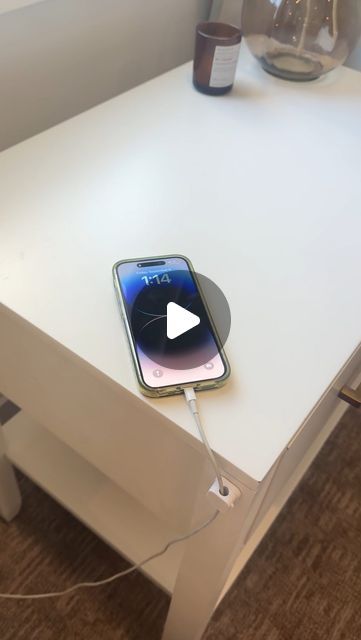 an iphone charging on top of a white table