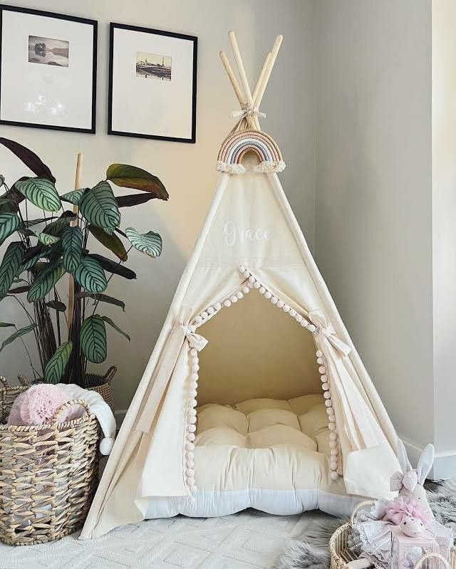 a teepee tent in the corner of a room next to a potted plant