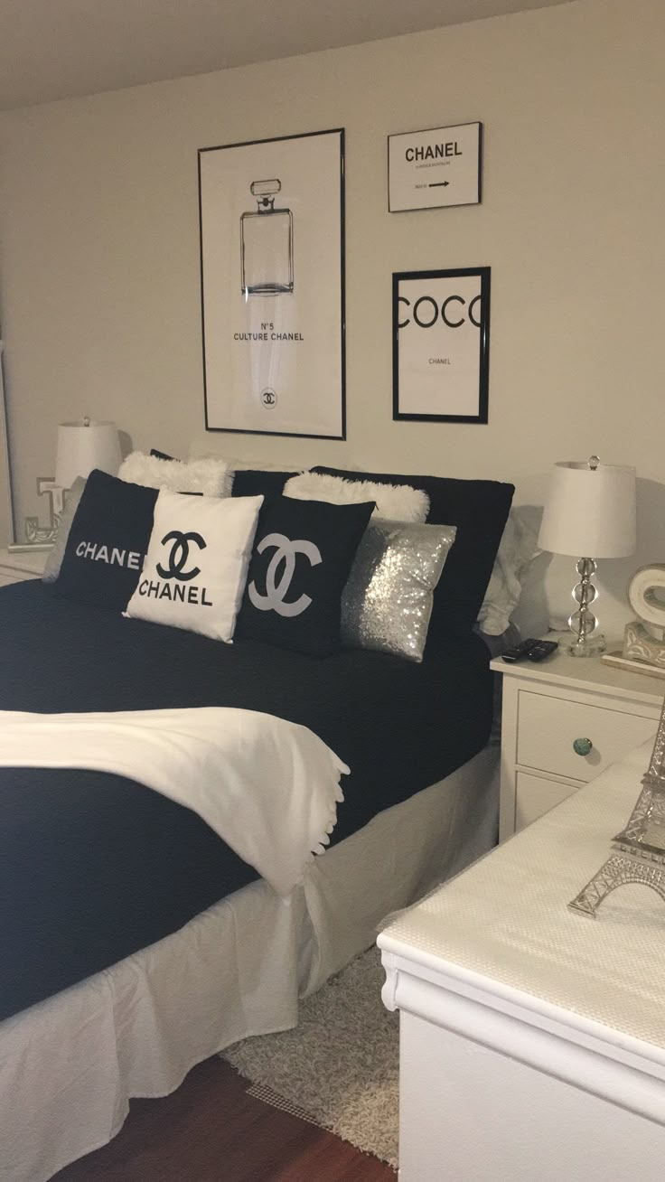 a bed with black and white pillows in a bedroom next to pictures on the wall