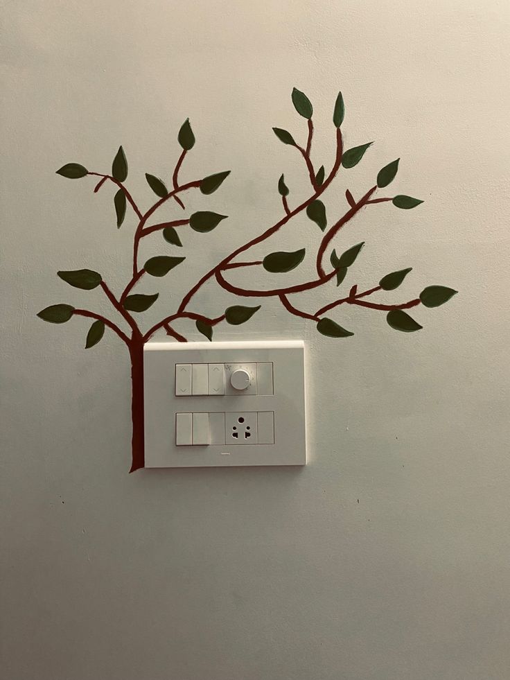 a white electrical outlet with green leaves on it and a light switch in the wall