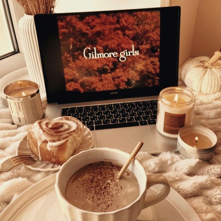 a laptop computer sitting on top of a table next to a cup of hot chocolate