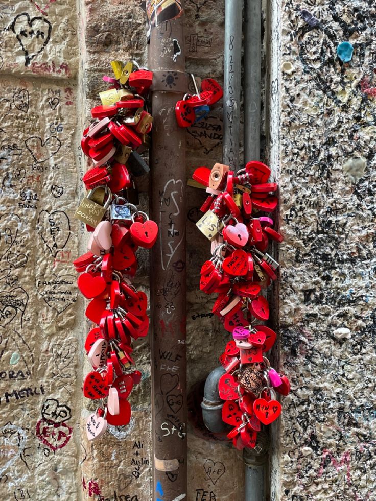 a bunch of love locks attached to a wall with lots of red hearts on it