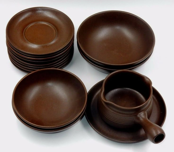 a set of brown dishes and cups on a white surface