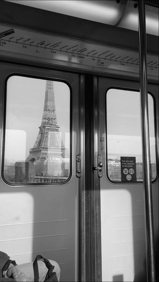 black and white photograph of the eiffel tower seen through double doors on a train