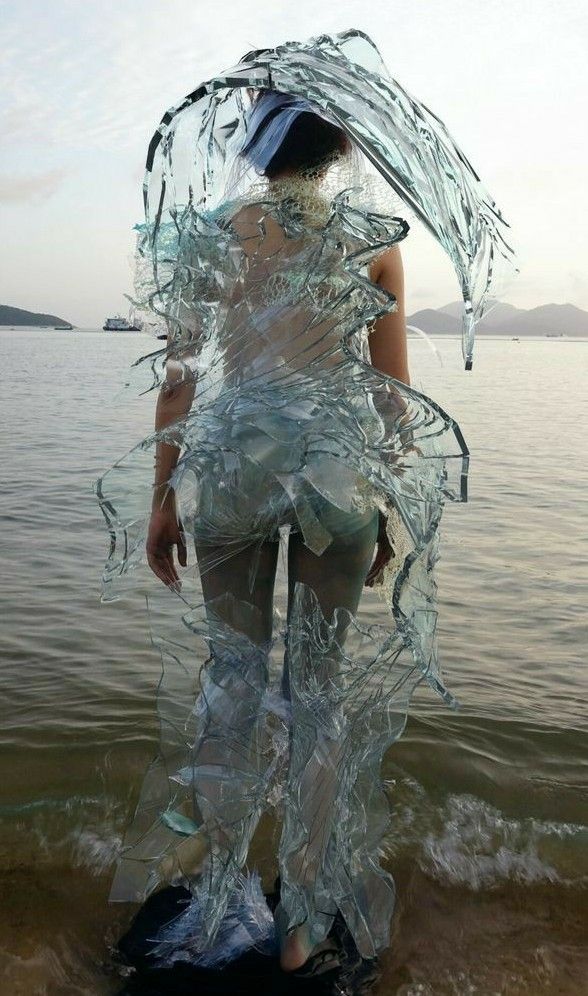 a woman is standing on the beach with her dress made out of plastic wrappers