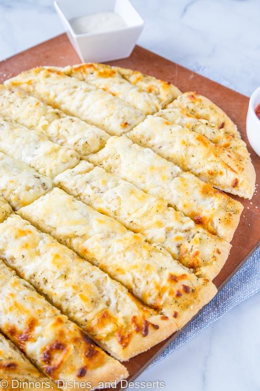 a pizza sitting on top of a wooden cutting board next to a bowl of sauce