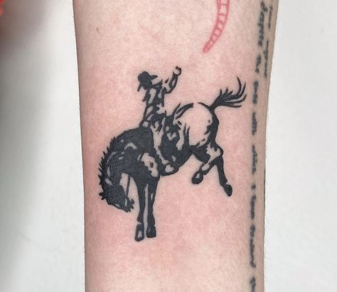 a person with a tattoo on their arm riding a horse