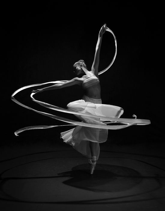 a woman in white dress holding a hula hoop and spinning it with her hands