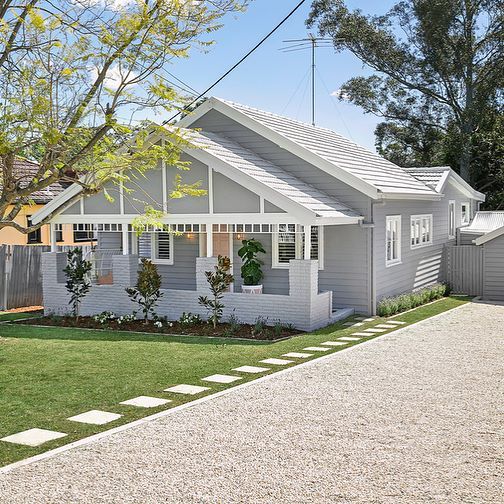 a white house with a driveway and trees in the background