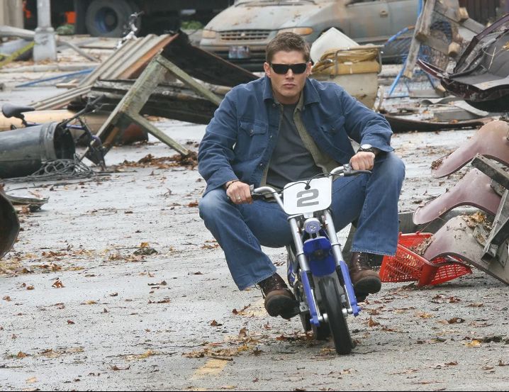 a man riding a motorcycle through a junk yard