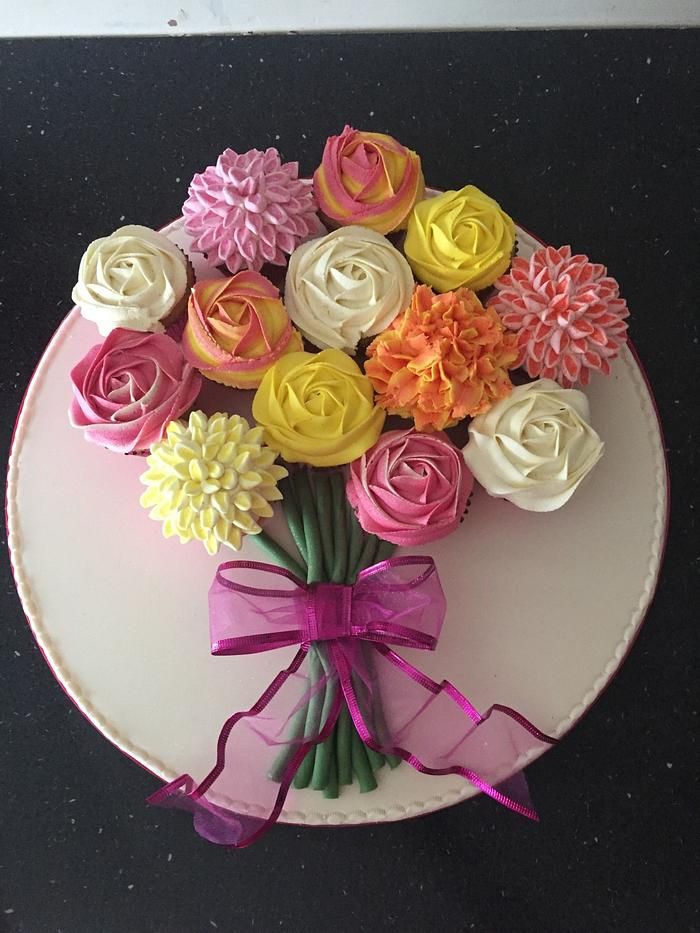 a white plate topped with cupcakes covered in frosting and colorful icing