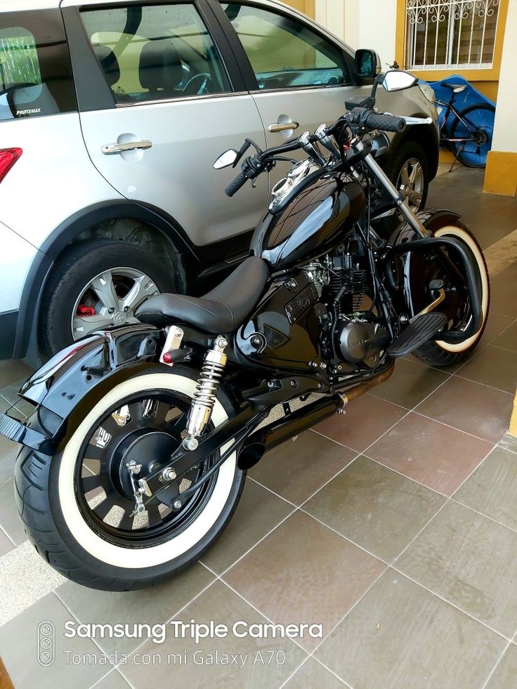 a black motorcycle parked next to a silver car