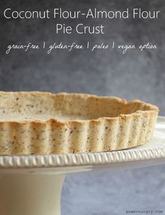 a pie crust sitting on top of a white cake plate with text overlay that reads coconut flour - almond flour pie crust