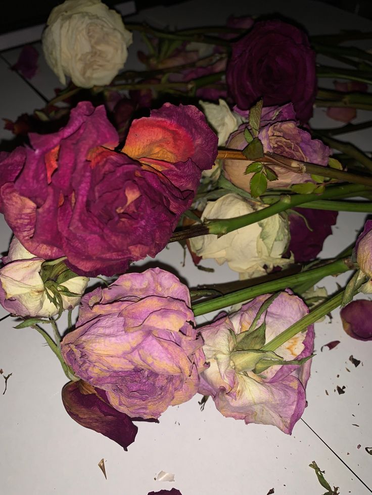 some pink and white flowers are laying on a table top with petals scattered around them