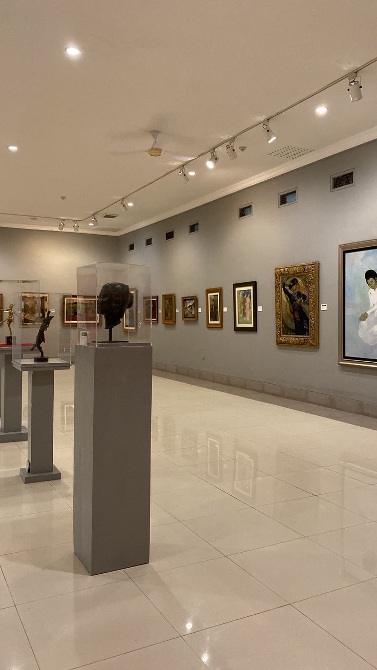 an art gallery with paintings and sculptures on the walls, in front of a white tiled floor