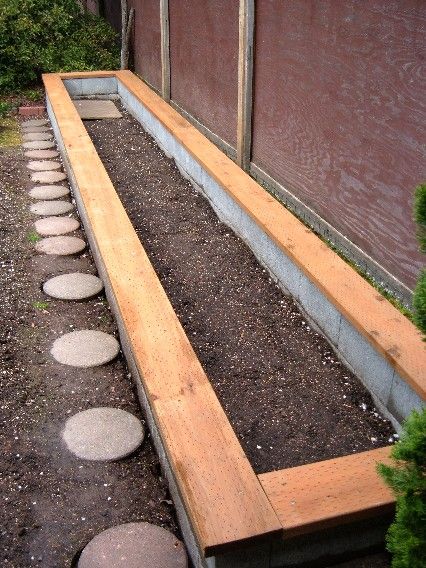 a wooden bench sitting in the middle of a garden with stepping stones on the ground