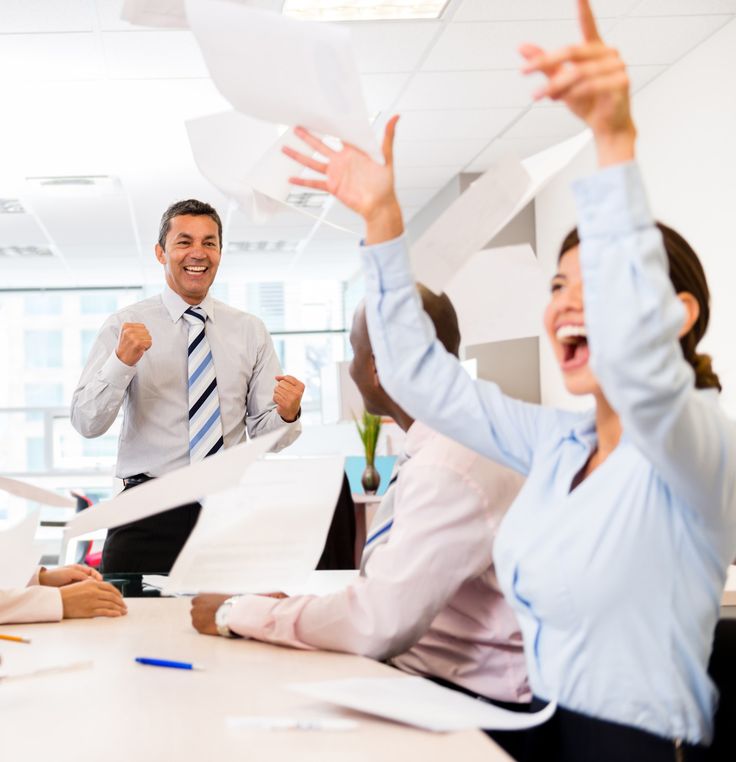 a group of people sitting around a table with papers in the air