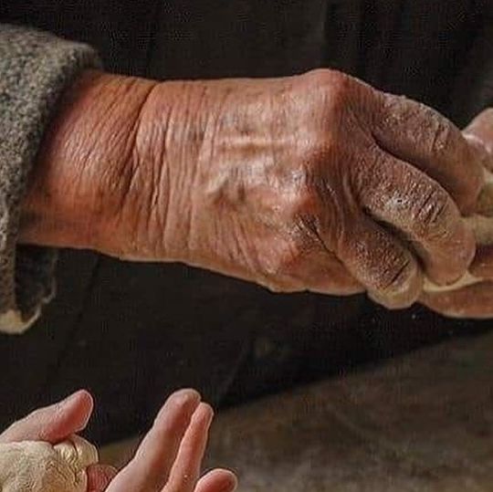 an older person holding a baby's hand and reaching for something in the other hand