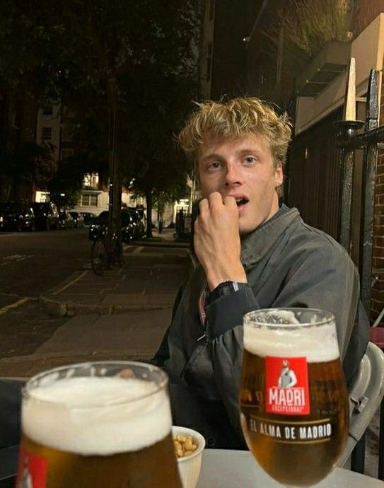 a man sitting at a table with two beers in front of him