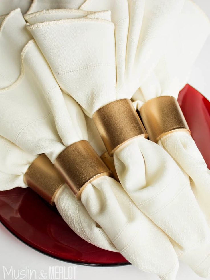 two napkins on top of a red plate with gold rings and white napkins