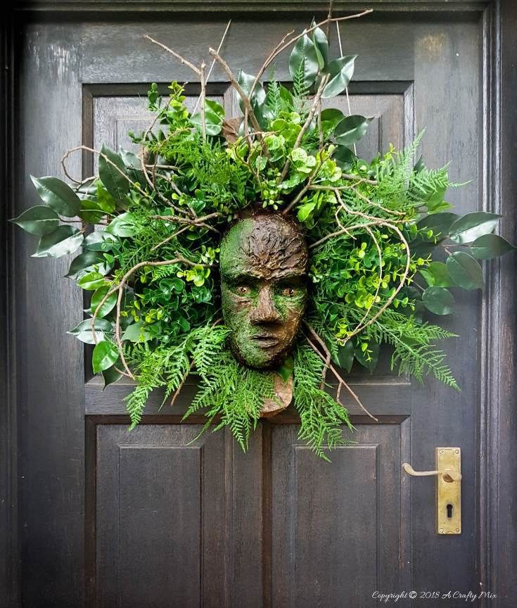 a green man's head is surrounded by greenery on the front door to a house