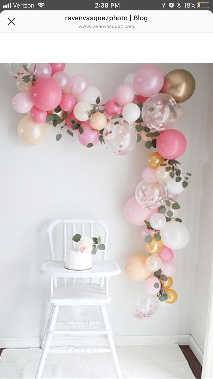 a white chair sitting in front of a balloon arch