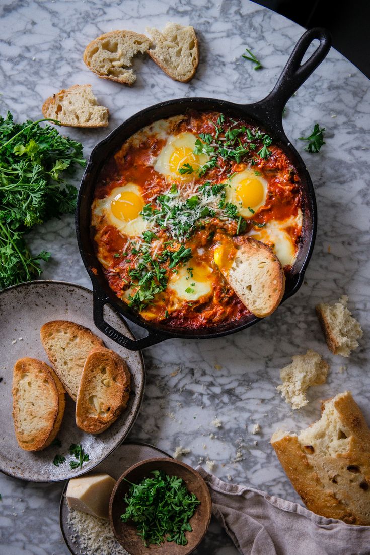 an iron skillet filled with eggs and bread on top of a marble countertop