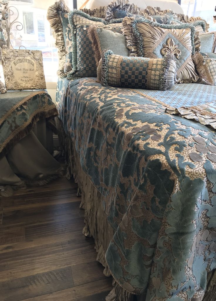 a bed with blue and gold comforters in a bedroom next to a wooden floor