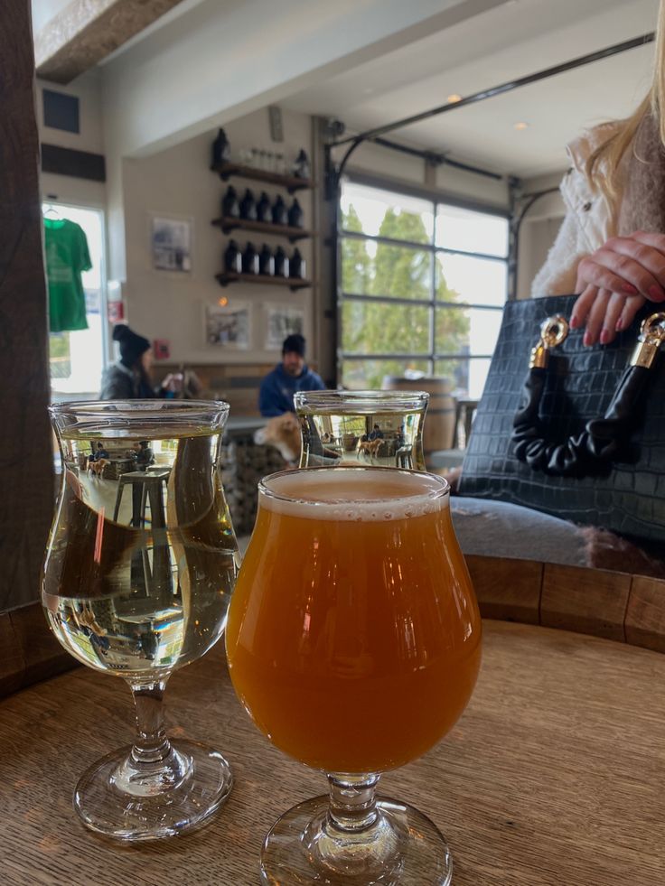 two glasses of beer sitting on top of a wooden table