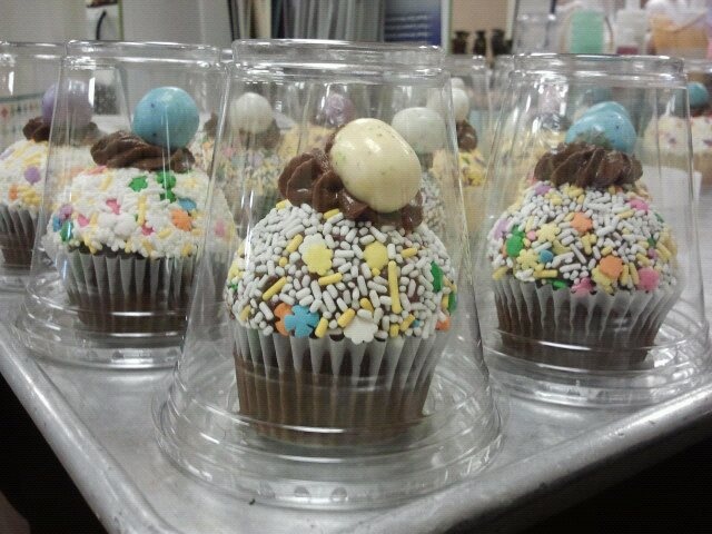 four cupcakes with frosting, sprinkles and decorations on them