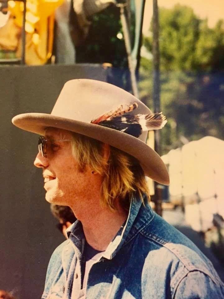 a man wearing a hat and holding a cell phone in his hand while standing next to a truck