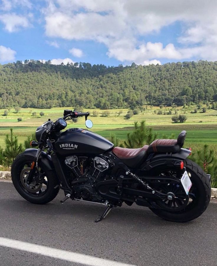 a motorcycle is parked on the side of the road in front of some hills and trees