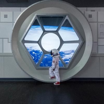 an astronaut standing in front of a window looking at the earth