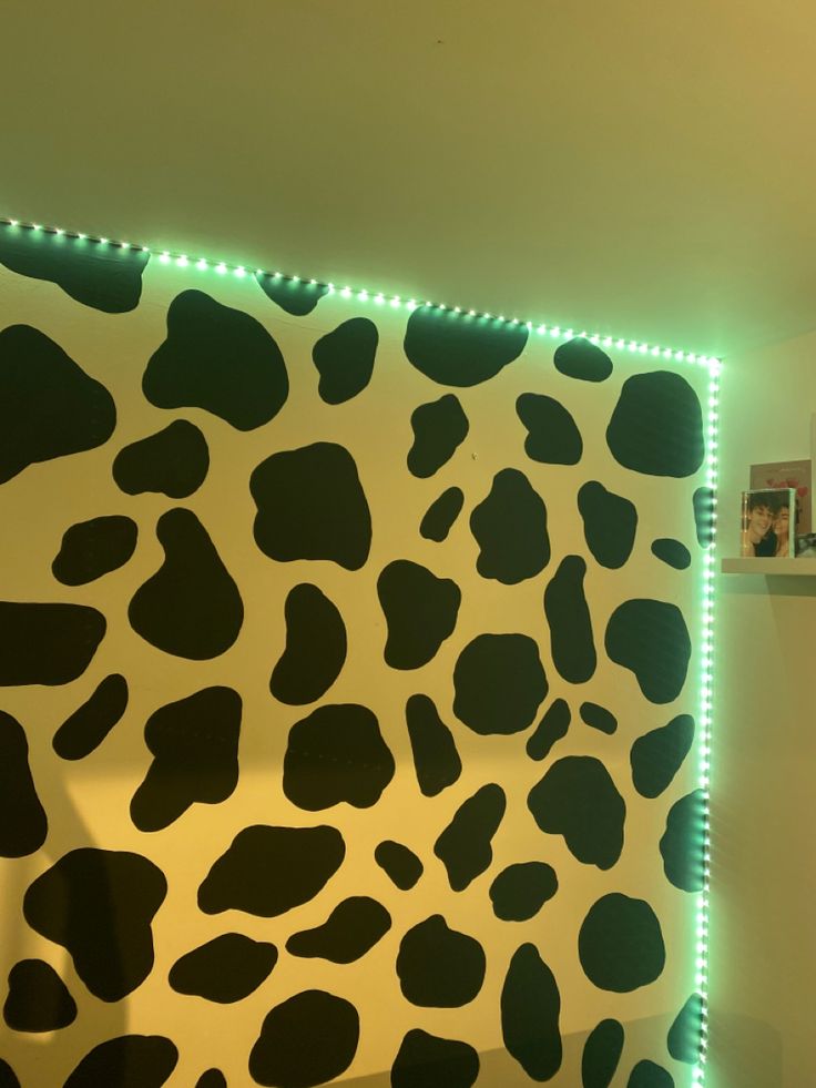 a cow print wall with green lights on it's sides and some pictures on the wall