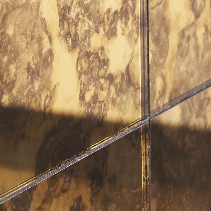 the shadow of a person standing in front of a wall with marble tiles on it