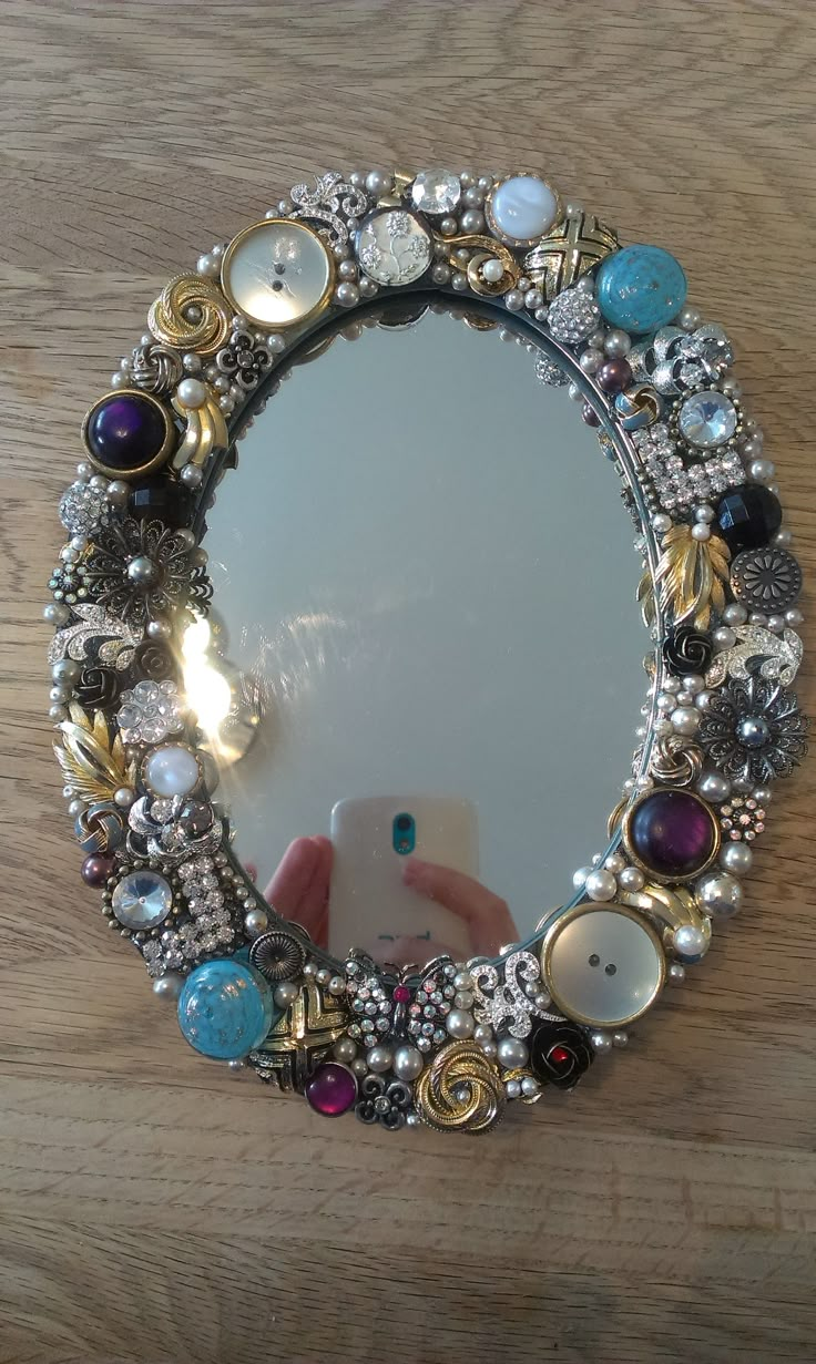 a mirror that is sitting on top of a wooden table with beads and stones around it