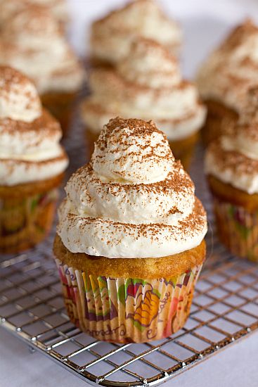 cupcakes with white frosting and sprinkles on a cooling rack