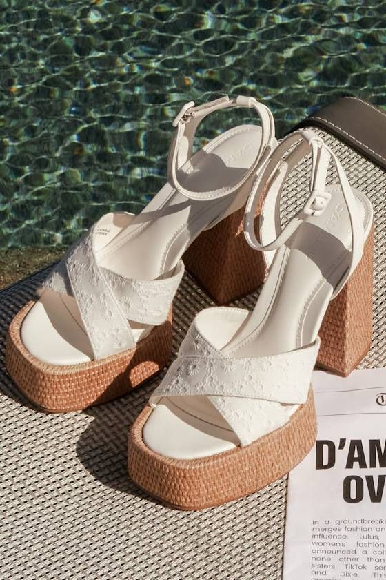 A summer spent with the D'Amelio Footwear Raela White Eyelet Embroidered Platform Ankle Strap Sandals is a summer spent in sensational style! These too-cute sandals start with a raffia-wrapped, 1.5"" toe platform that creates a square footbed, along with floral eyelet embroidered vamp straps that crisscross atop an open-toe upper. A supportive heel strap holds an adjustable ankle strap that secures with a white buckle, all above a matching raffia-wrapped, sky-high block heel. 5" raffia-wrapped h Summer Beach Lace-up Wedge Sandals, Summer Beach Lace-up Sandals With Ankle Strap, Closed Toe Lace-up Sandals For Beach Vacation, Casual Open Heel Lace-up Sandals For Vacation, Beach Closed Toe Lace-up Sandals, Closed Toe Synthetic Lace-up Sandals For Beach, White Platform Sandals For Summer, Summer Lace-up Open Toe Sandals For Beach Season, White Platform Sandals For Vacation