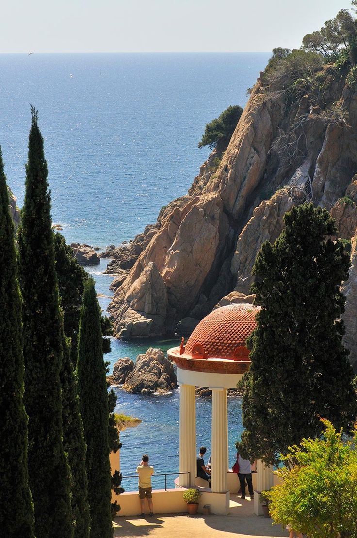 two people are standing on the steps overlooking the water and trees in front of them