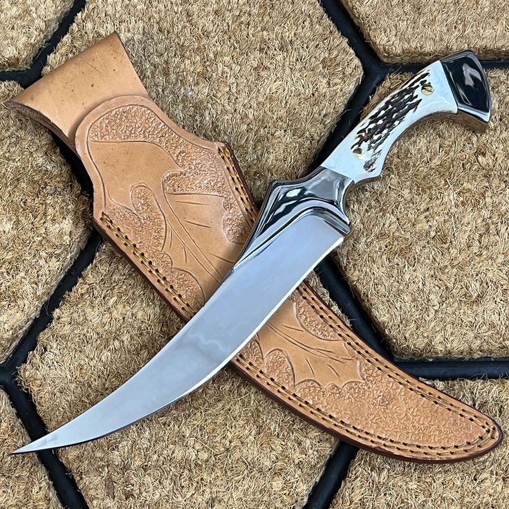 a knife that is laying on the ground with a leather sheath around it's blade