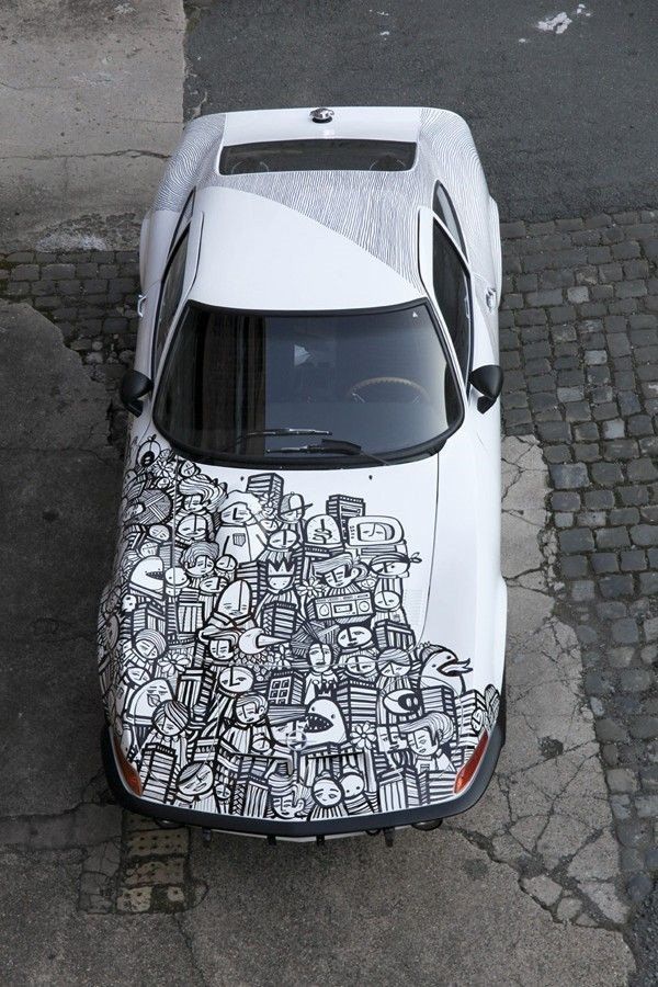 an aerial view of a white car with black and white graffiti on it's hood